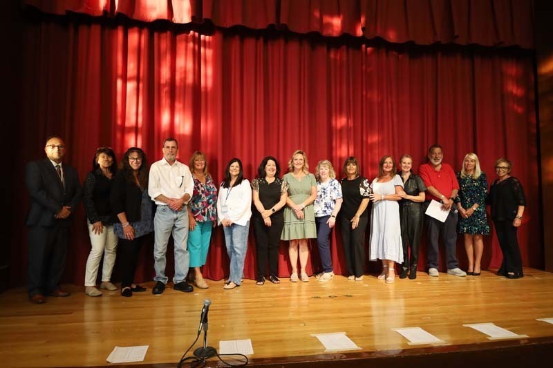 Students on stage in front of red curtain.