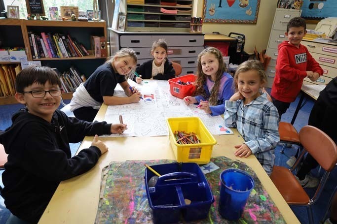 Students smiling at camera while drawing.