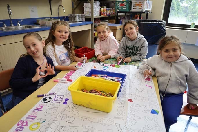Students smiling at camera while drawing.