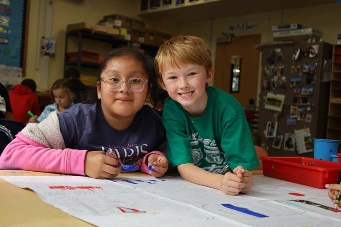 Students smiling at camera while drawing.