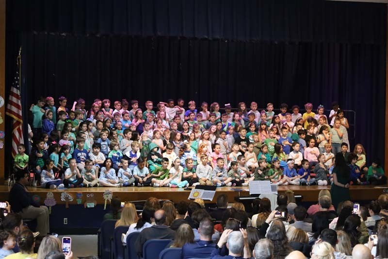 3)	In the auditorium, kindergartners put their hands over their hearts to recite an Earth Day pledge. 