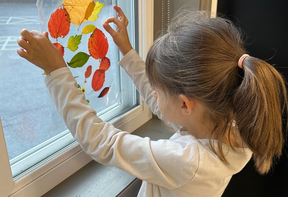 Child with leaf suncatcher craft project