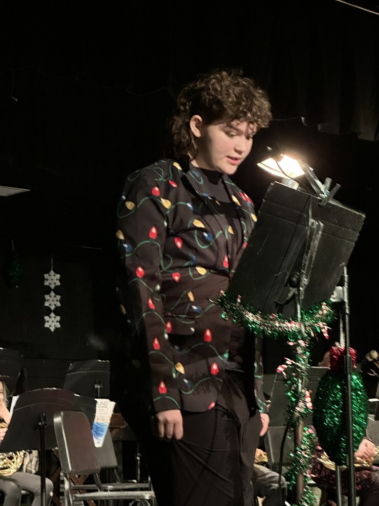 The image shows a student speaking at the band concert.
