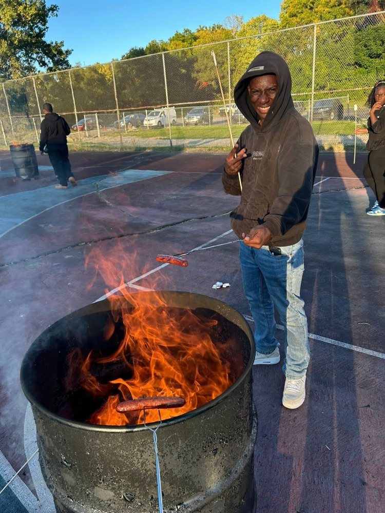 Student roasting a hotdog and holding a peace sign