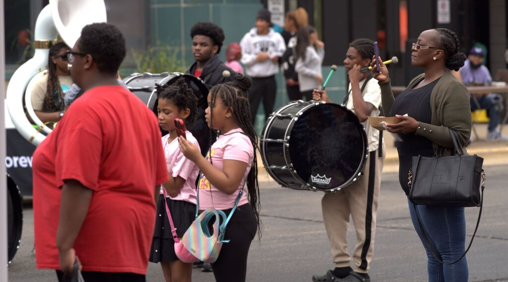 Students, families, and community members gathering near student musicians performing at a BHAS outdoor event.