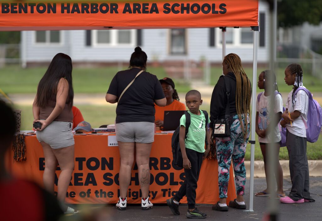 Families and students visiting a Benton Harbor Area Schools information and registration table at an outdoor event.