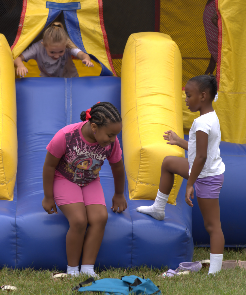 Children playing together on a colorful inflatable attraction at a BHAS community event.