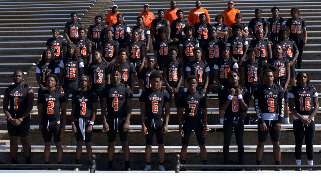Benton Harbor Tigers football players and coaches posing for a team photo in the stadium bleachers.