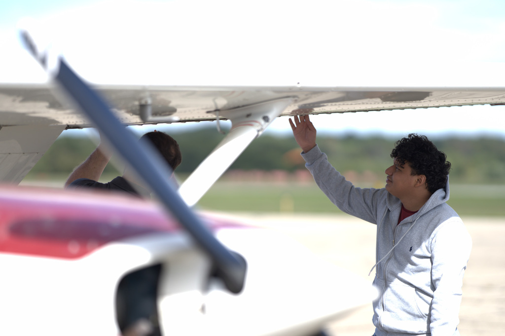 Student inspecting the wing of a training aircraft as part of a preflight check.