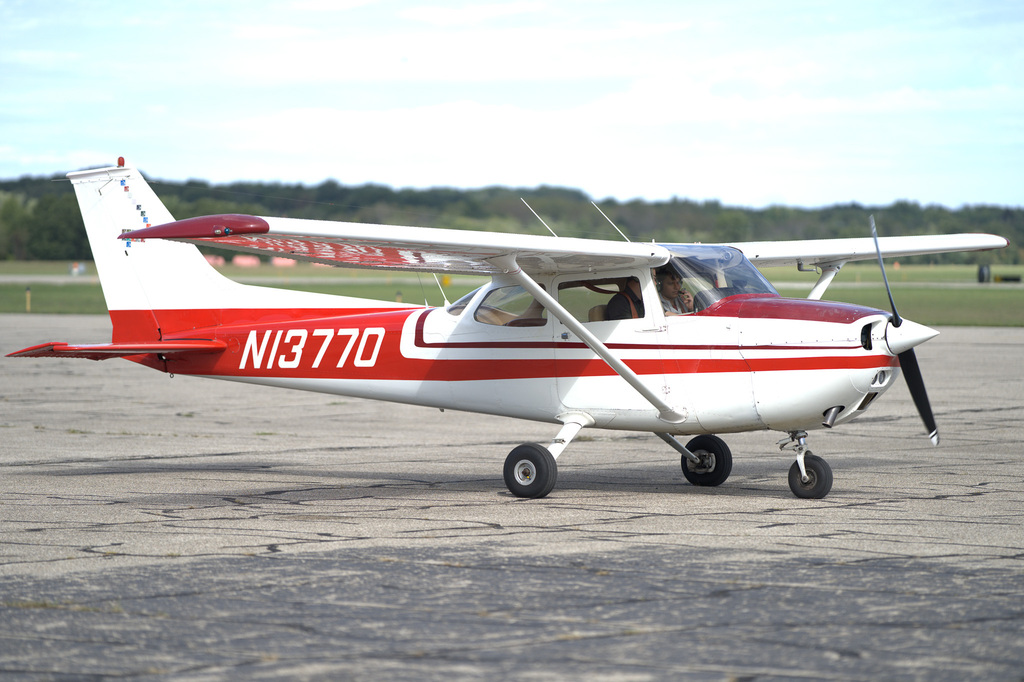 Red-and-white training aircraft taxiing on the runway during a student aviation experience.