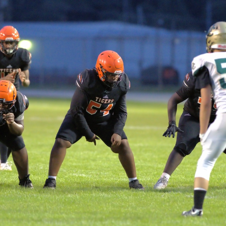 Benton Harbor Tigers football players line up against an opposing team in white and green uniforms before the snap.