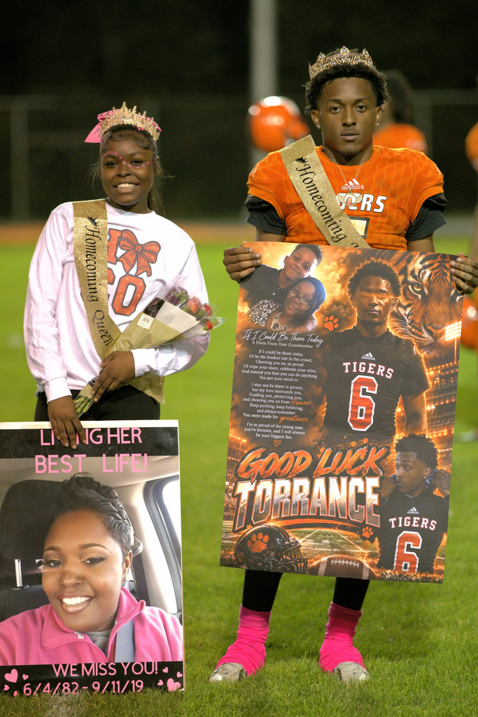 A crowned Benton Harbor football player wearing jersey number 6 stands beside a smiling homecoming queen holding flowers. Both display personalized tribute posters.