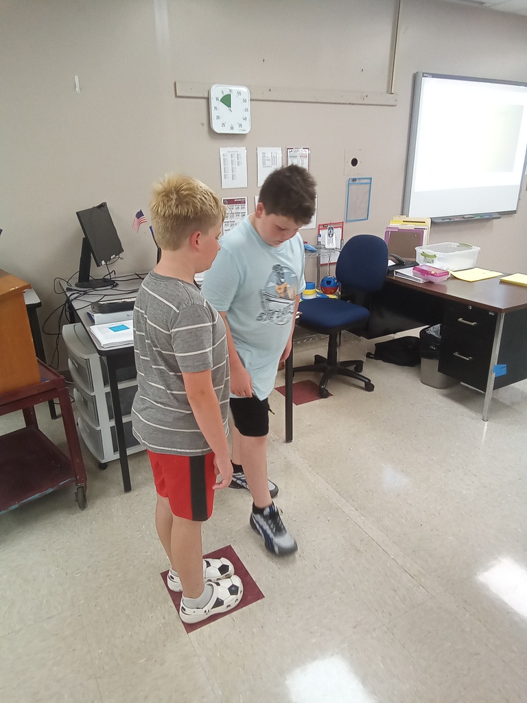 One student is standing on a small square as another looks on as part of this activity