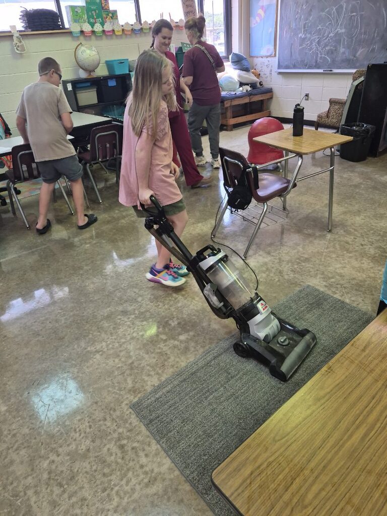 A student is practicing life skills by vacuuming a carpet
