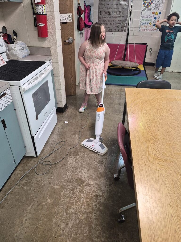 A student is practicing life skills by mopping the floor