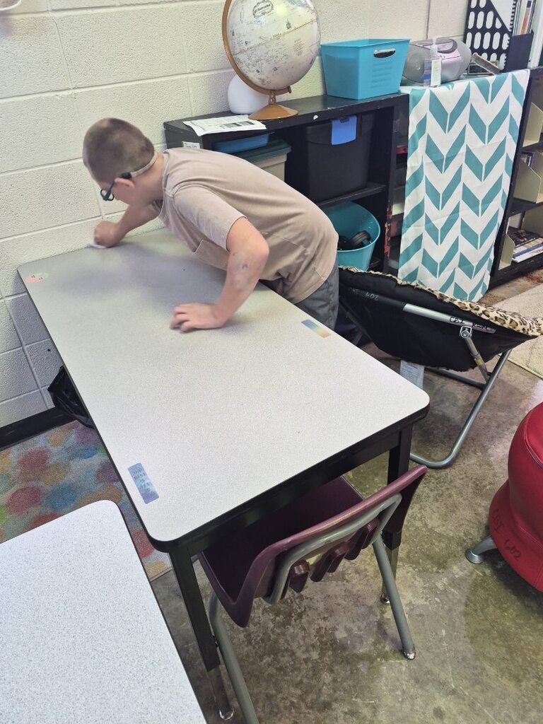 A student practices life skills by helping to clean off a table