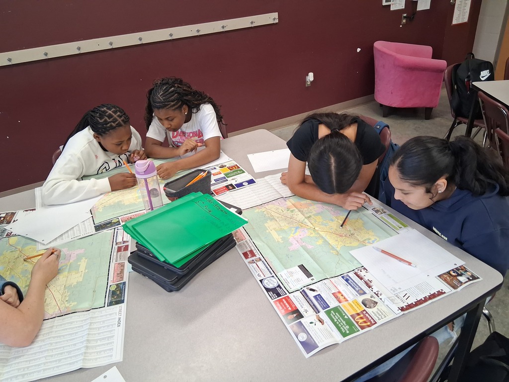 Two groups of students are closely studying maps of Benton to complete the activity