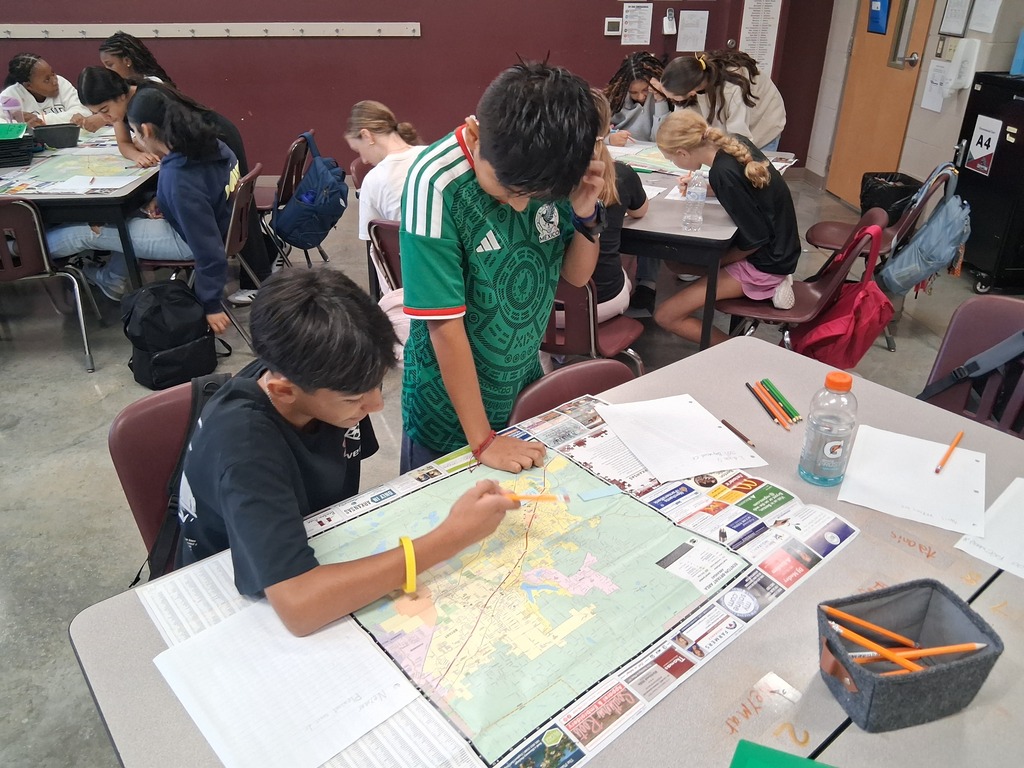 Two students stand over a map of Benton as they attempt to locate local landmarks
