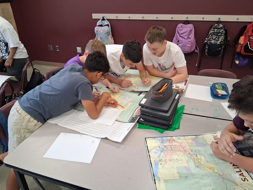 Four students stand over a map of Benton as they attempt to locate local landmarks