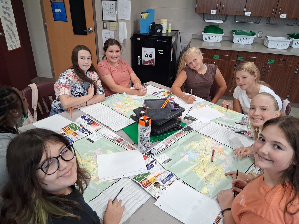 A group of students smiles at the camera as they participate in the map activity