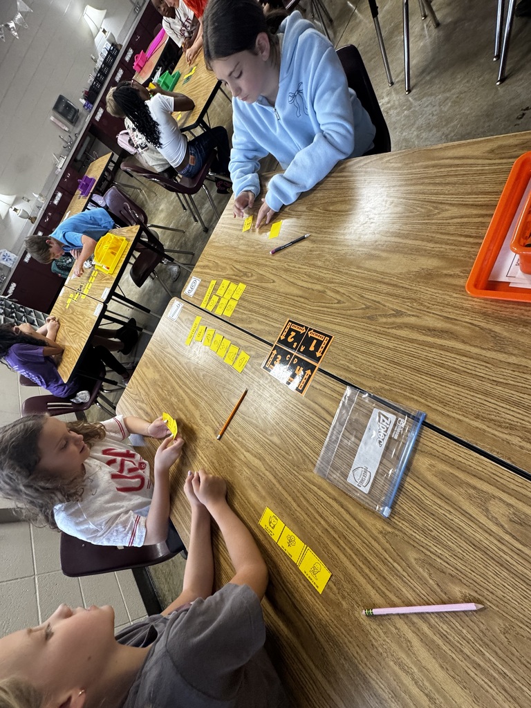 Three students are sitting in their table groups sorting cards as they learn about observations and inferencing