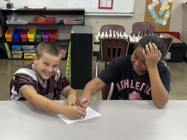 Two students participate in Mrs. Heard's 2 and a crayon activity in GT. They are both holding the same crayon as they draw a picture.