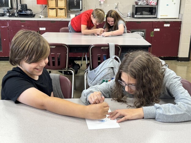 Two students participate in Mrs. Heard's 2 and a crayon activity in GT. They are both holding the same crayon as they draw a picture.