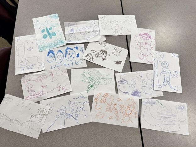 Student exemplars are spread out on a table from the 2 and a crayon activity in Mrs. Heard's GT class.