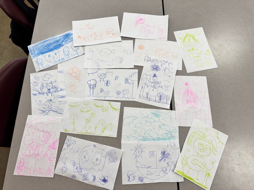 Student exemplars are spread out on a table from the 2 and a crayon activity in Mrs. Heard's GT class.