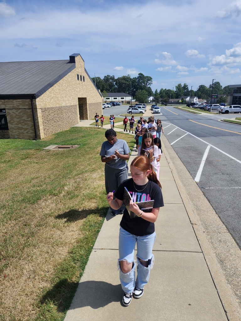 A group of students are walking along the side walk around the middle school observing life.