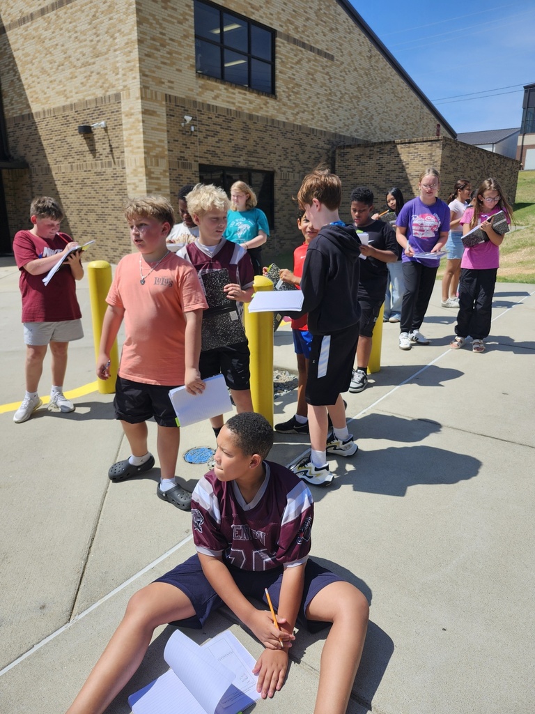 A group of students are walking along the side walk around the middle school observing life.