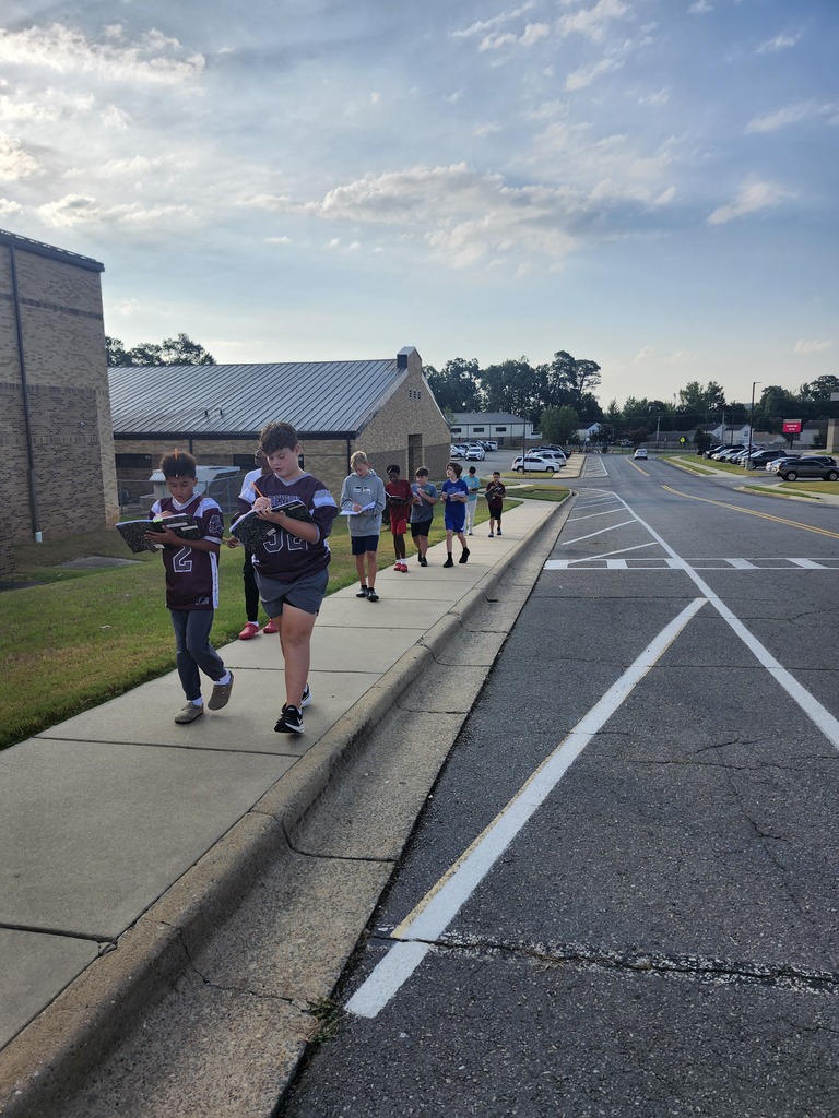 A group of students are walking along the side walk around the middle school observing life.