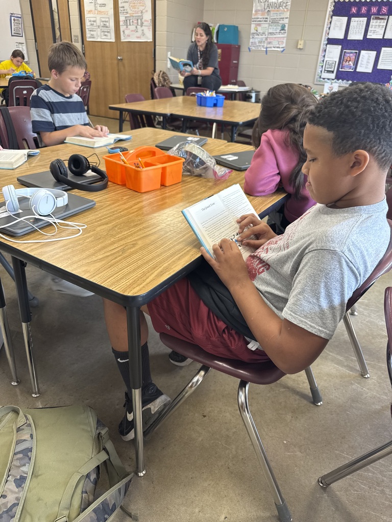 A group of students is sitting at their table reading the book Wonder in their ELA class