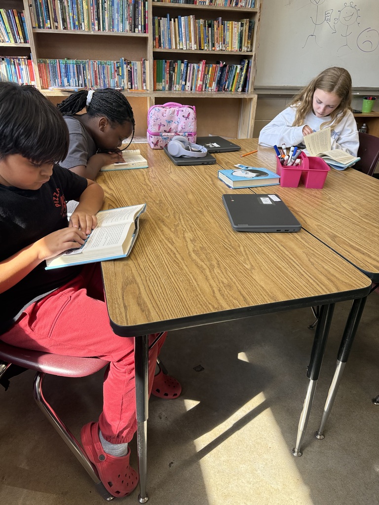 A group of students is sitting at their table reading the book Wonder in their ELA class