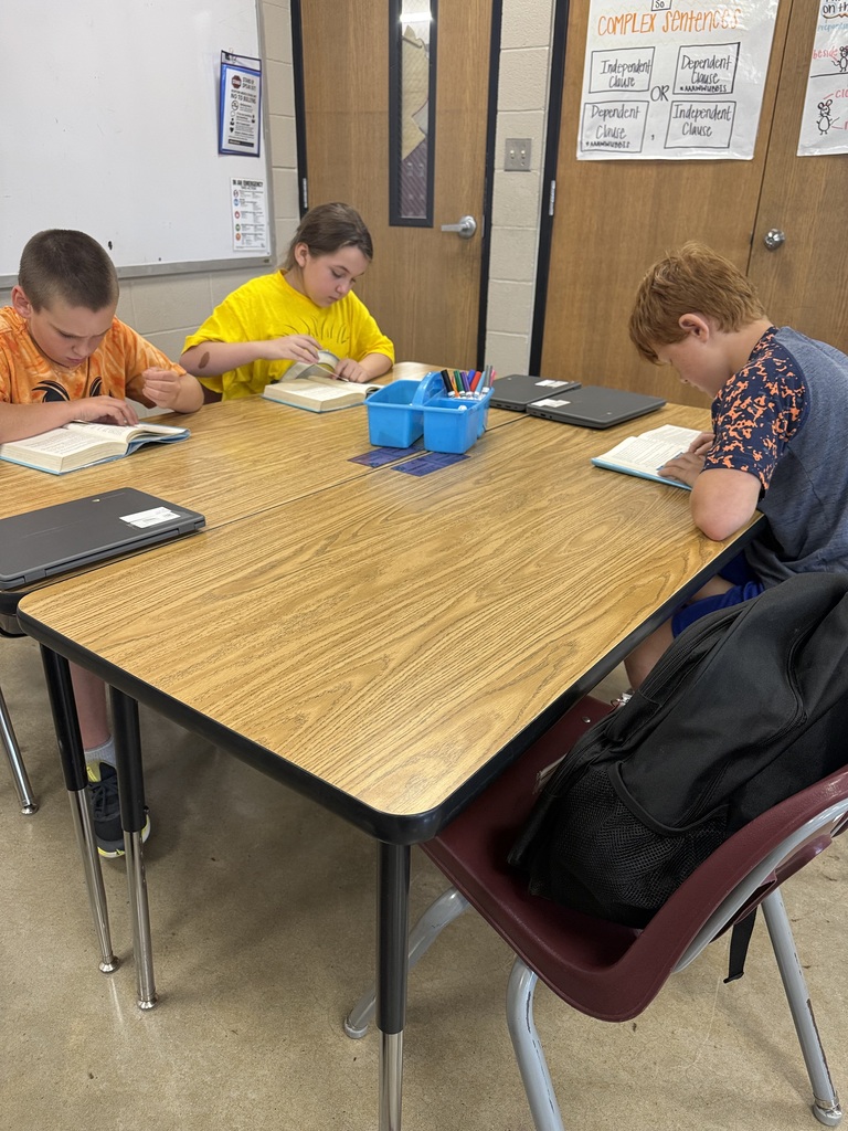 A group of students is sitting at their table reading the book Wonder in their ELA class