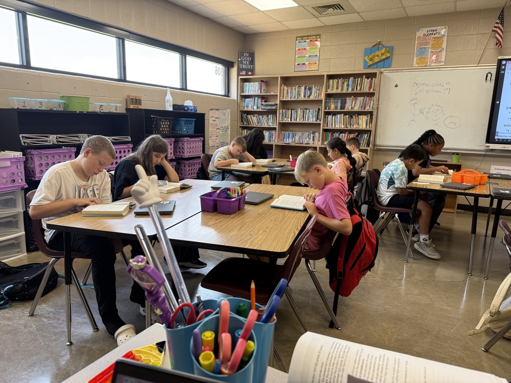 A group of students are sitting at their table reading the book Wonder in their ELA class