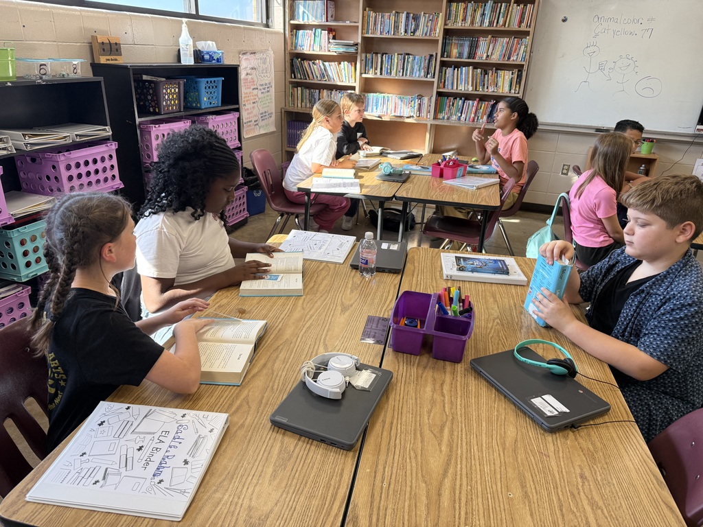 A group of students are sitting at their table reading the book Wonder in their ELA class