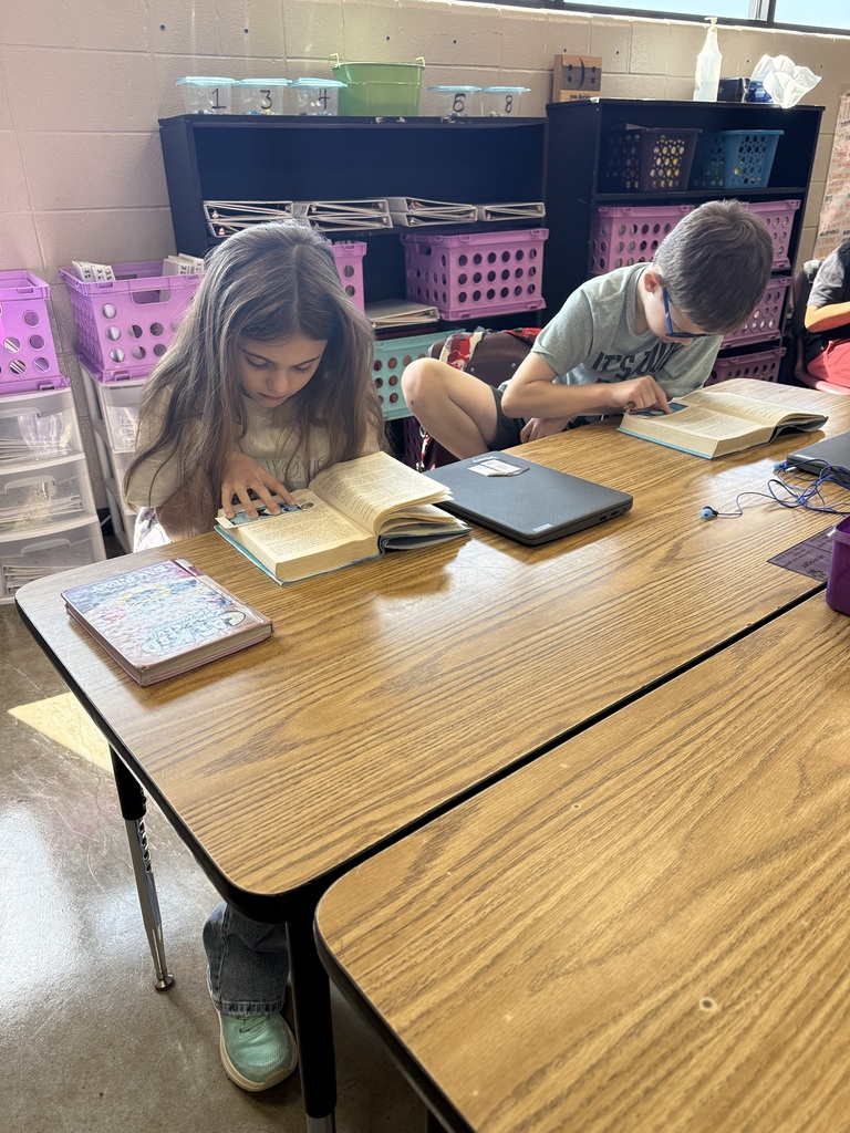 Two students is sitting at their table reading the book Wonder in their ELA class