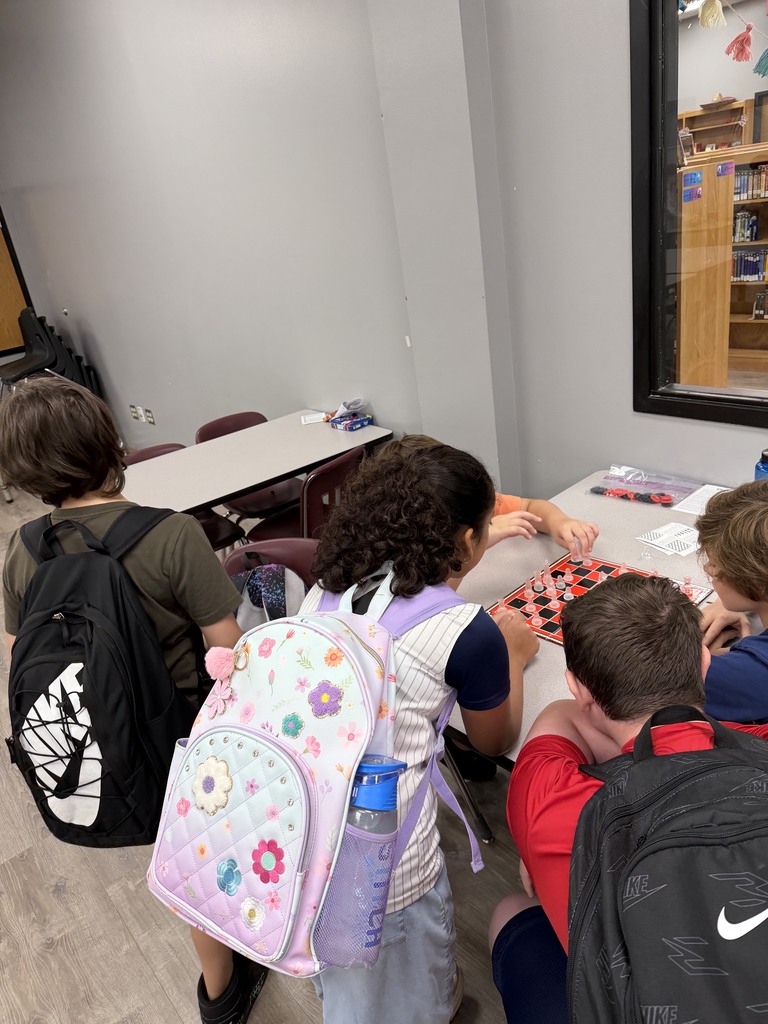 a group of students is watching two students play chess
