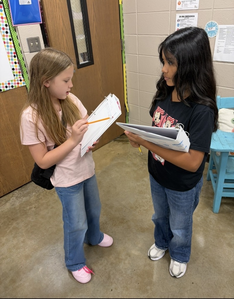 Two students are discussing their papers with one another