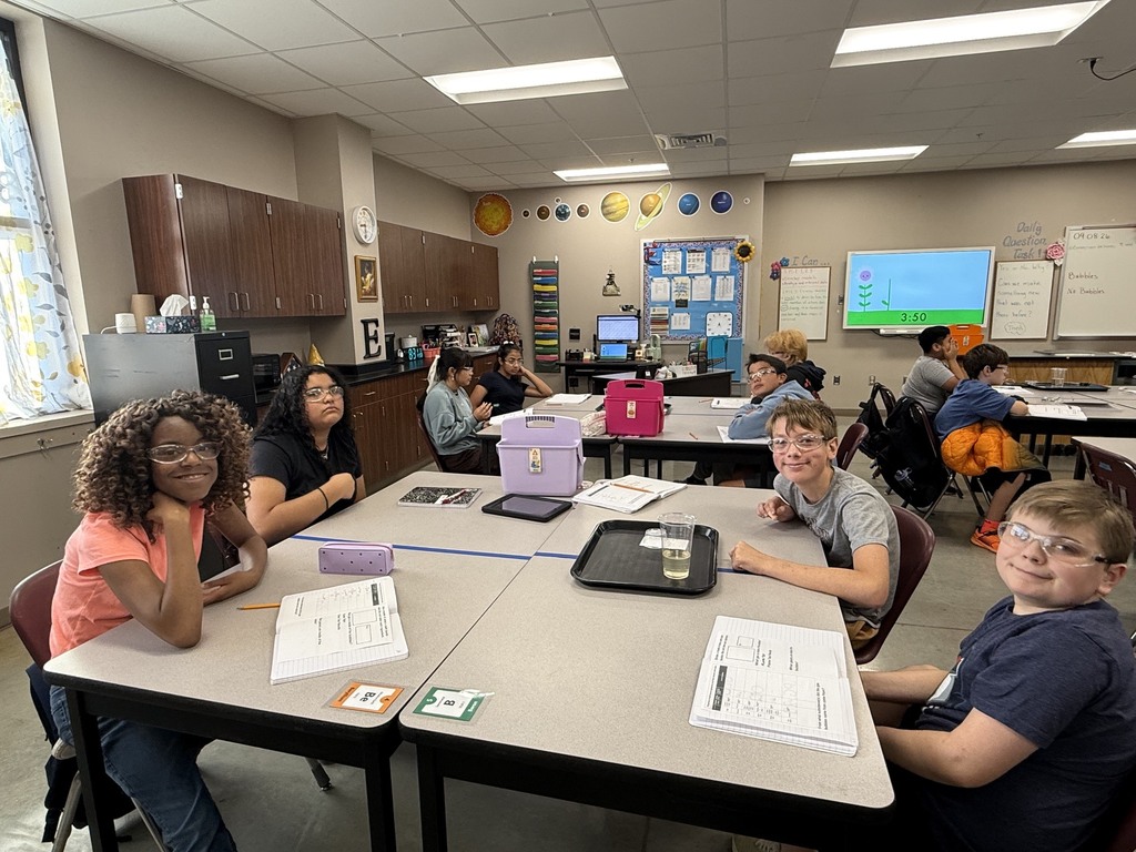 Students around the table in Mrs. Eddleman's class conducting a science experiment with bath bombs