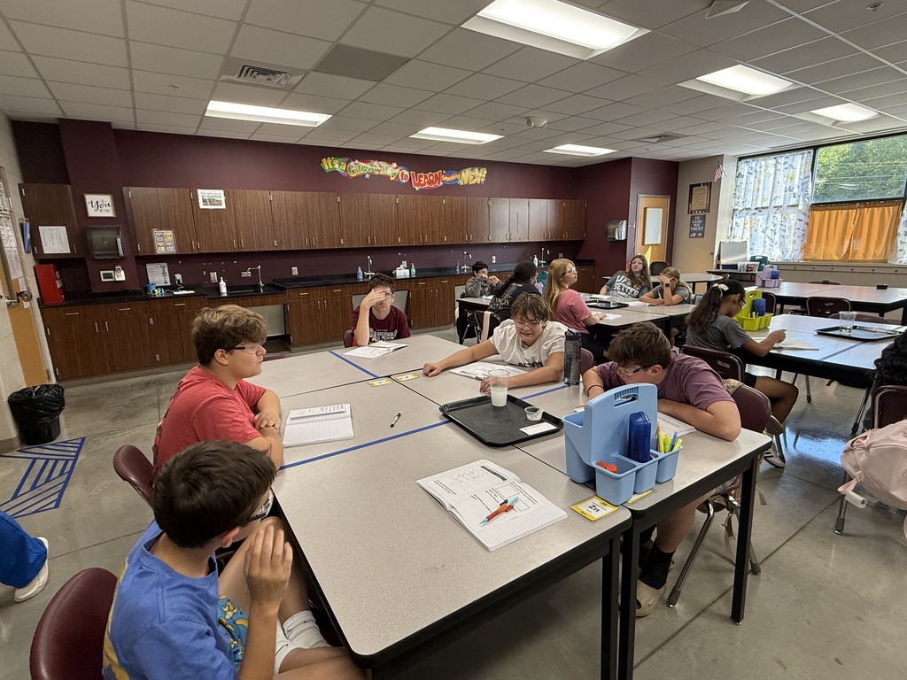 Students around the table in Mrs. Eddleman's class conducting a science experiment with bath bombs