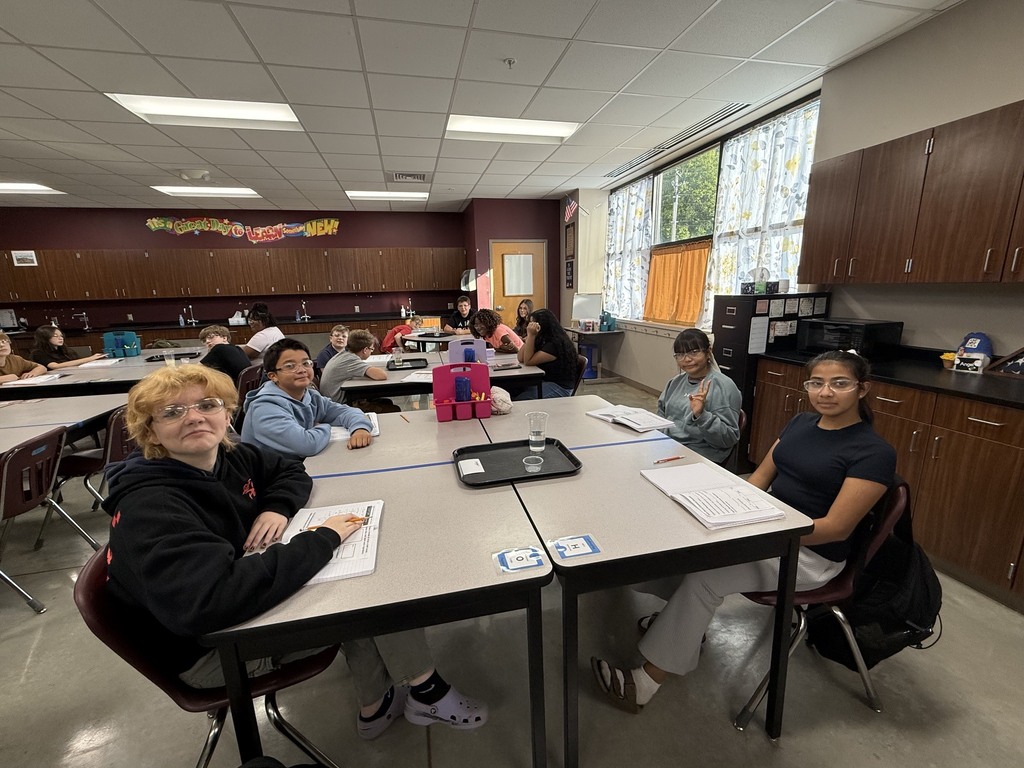 Students around the table in Mrs. Eddleman's class conducting a science experiment with bath bombs