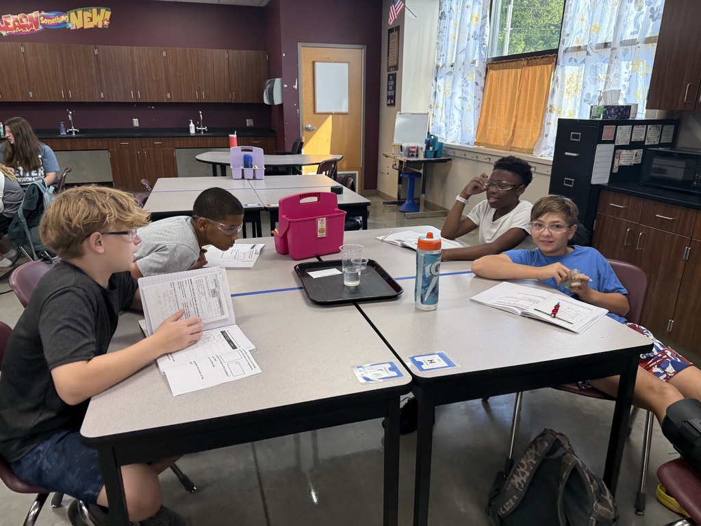 Students around the table in Mrs. Eddleman's class conducting a science experiment with bath bombs
