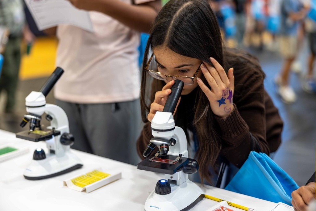 Student looks through a microscope at career fair event
