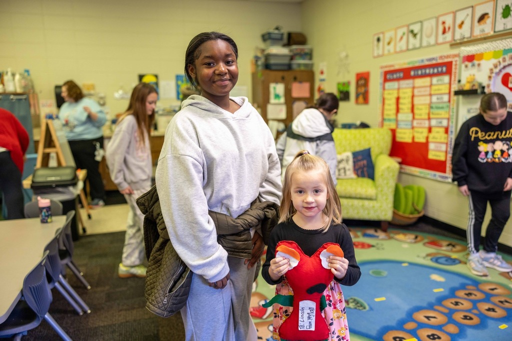 Sixth graders and pre-k students working on a sewing project together