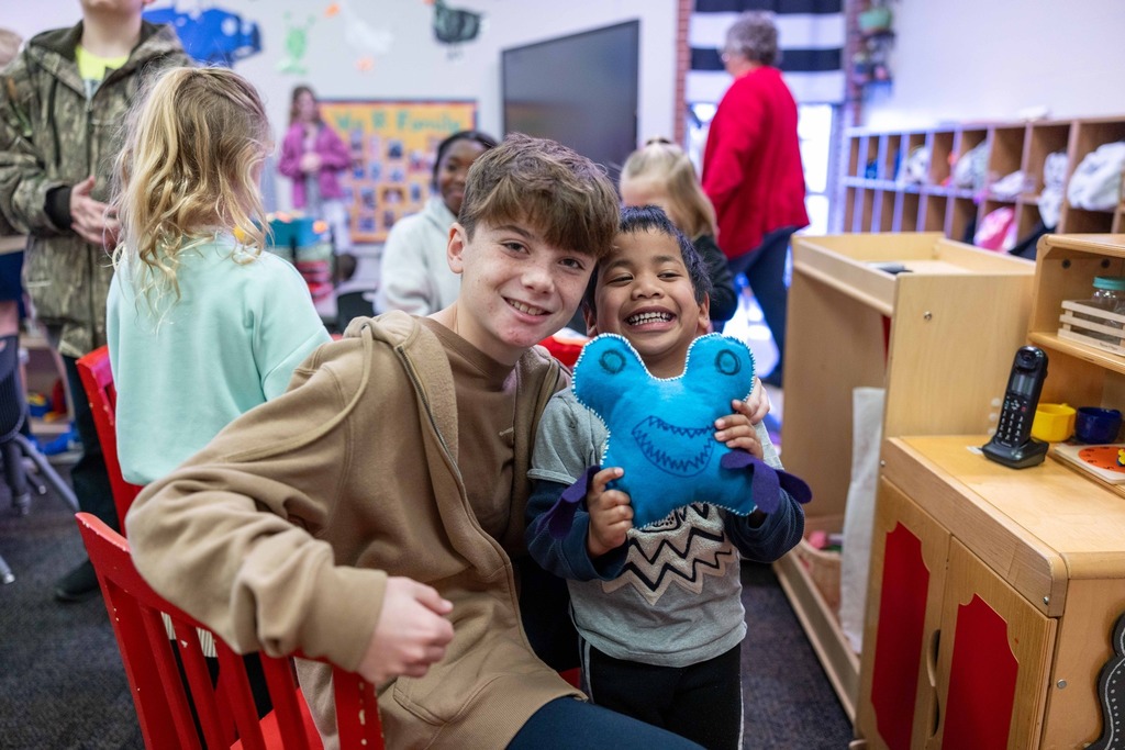 Sixth graders and pre-k students working on a sewing project together