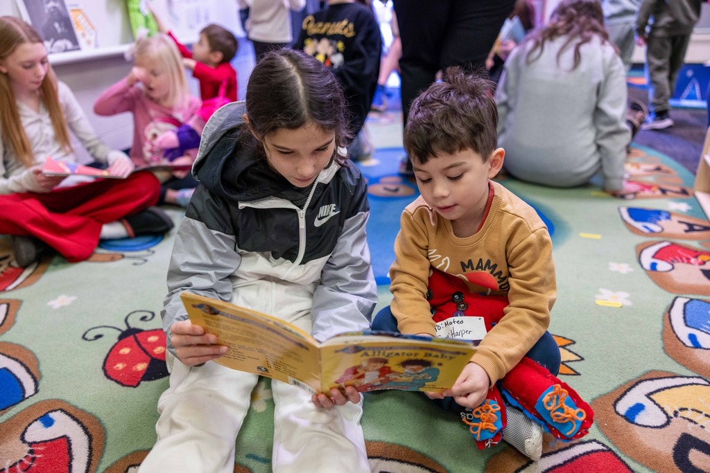 Sixth graders and pre-k students working on a sewing project together