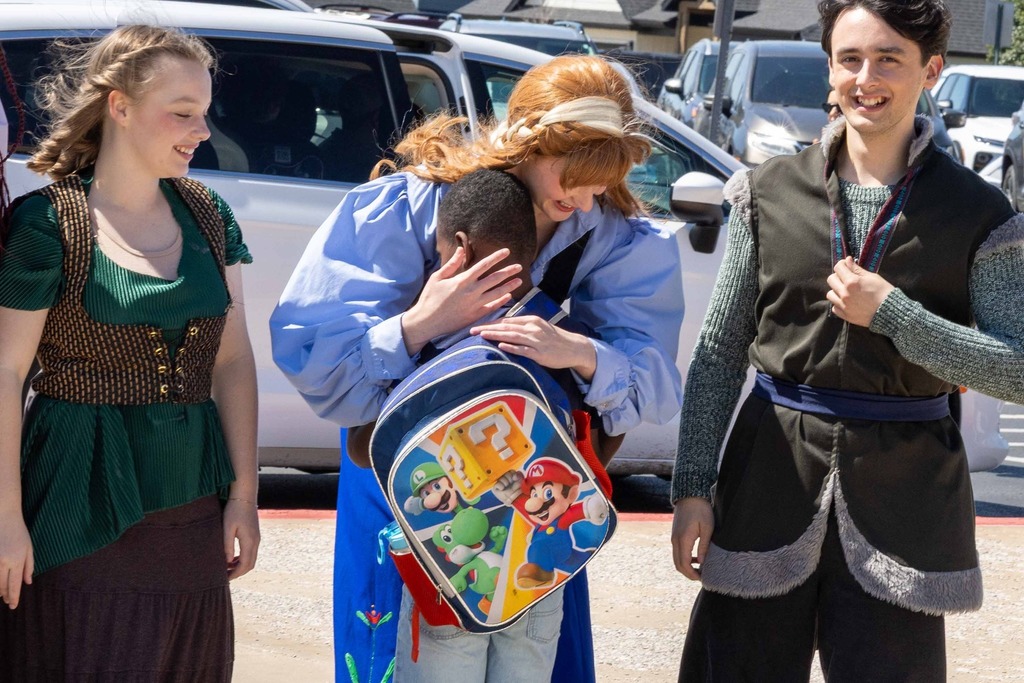 Cast of Frozen hugging students from 