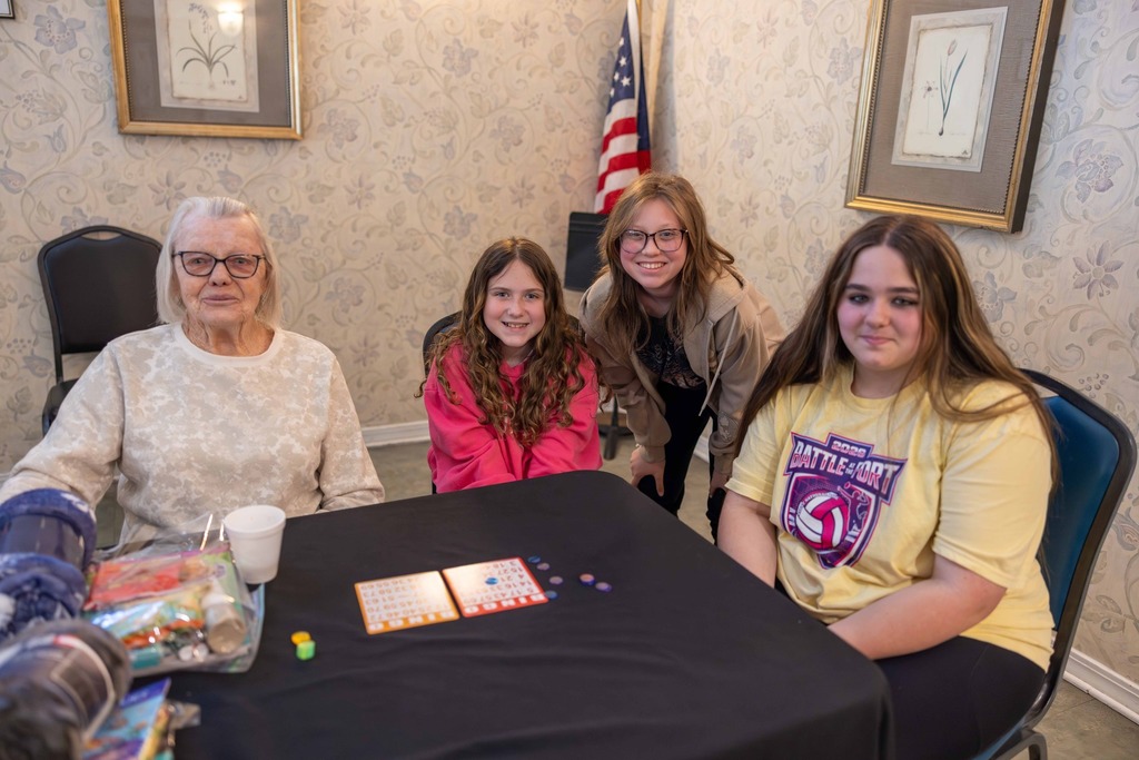 Students playing Bingo with a resident of a local senior living center